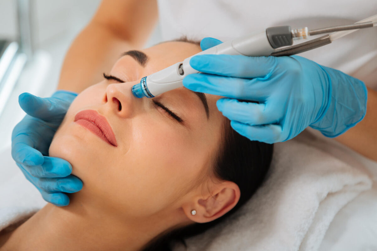 Delighted nice woman lying on the medical bed with her eyes closed while having hydrafacial