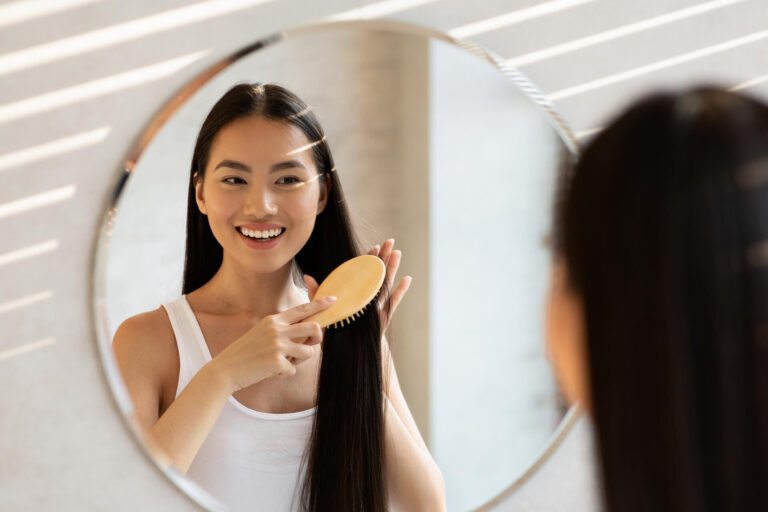 Cheerful asian lady with beautiful long hair standing in front of mirror