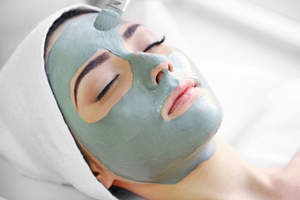 Young woman with nutrient facial mask in beauty salon